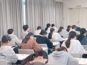 ⑤熱心にメモを取る学生